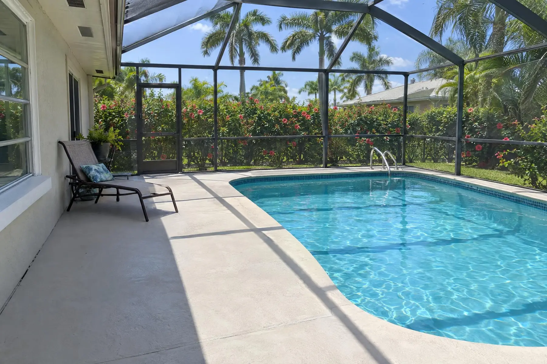 A level concrete pool deck beside a screened pool
